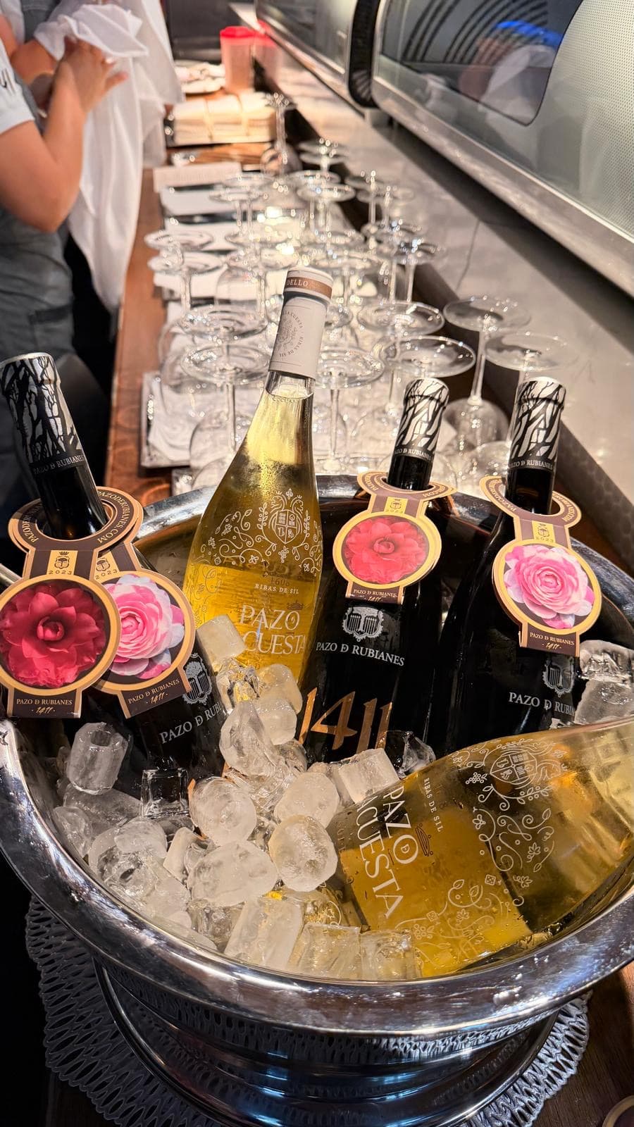 Bottles of white and sparkling wine chilling in an ice bucket beside a laid table