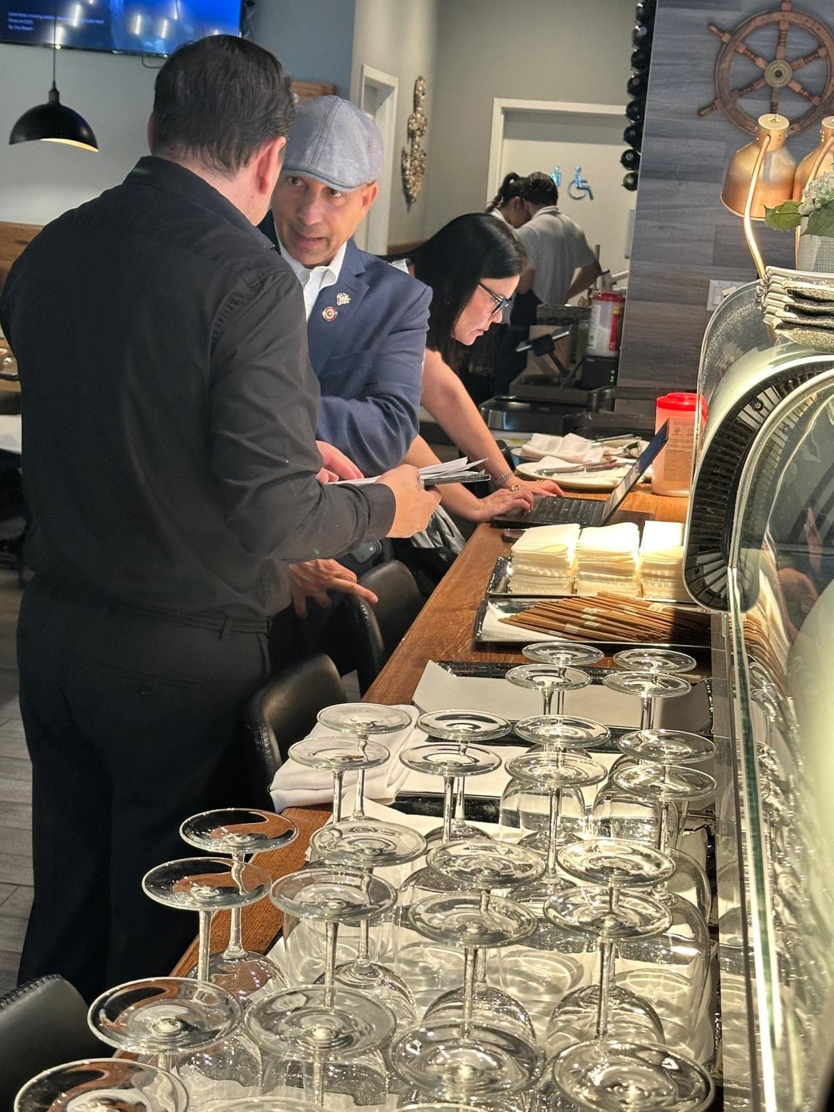 Staff working behind a counter stacked with tasting glasses before service